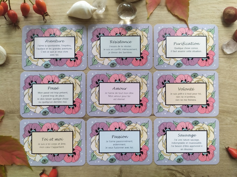 May include: A set of 10 cards with floral designs and inspirational quotes in French. Each card features a different quote about love, adventure, resistance, purification, the past, and more. The cards are printed on a light purple background with white stars.