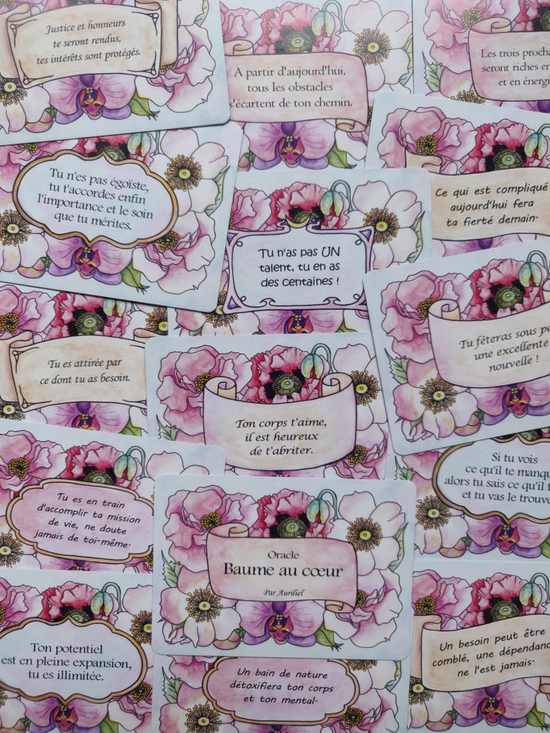 May include: A set of oracle cards with floral illustrations and inspirational messages. The cards are white with pink and purple flowers and have a light blue background. The text on the cards is in French. The cards are titled "Baume au c&oelig;ur" and "Oracle".