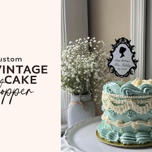 May include: A custom vintage cake topper with a black silhouette design and the text "Happy Birthday Mrs. Ashley May 15, 2023" sits atop a light blue cake with white frosting. The cake is on a white plate.
