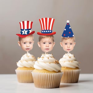 Könnte beinhalten: Drei Cupcakes mit weißem Zuckerguss und goldenen Streuseln, jeweils mit einem Papieraufsteller eines Kindergesichts. Die Gesichter tragen patriotische Kopfbedeckungen: zwei rot-weiß-blau gestreifte Zylinder und einen blauen Partyhut.