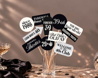 May include: A collection of black and white birthday photo booth props on wooden sticks, featuring text such as since 1986, farewell thirties, forever 39, 39-ish, look who's 40, the big four-uh-oh, goodbye youth, shit Nikki's old AF, I'm 29+, and welcome to the 40s club.