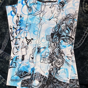 May include: Three art prints featuring a black and white illustration of a person's legs in jeans and a face with curly hair. The prints have a blue watercolor background and the word "BUTCH" in black letters.