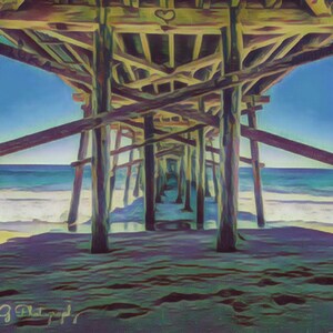 May include: A view from under a wooden pier, looking out towards the ocean. The sky is blue and the water is a turquoise color. The sand is a light brown color. The pier is made of weathered wood.