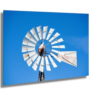 May include: A white windmill with a red and white Aermotor sign against a bright blue sky.
