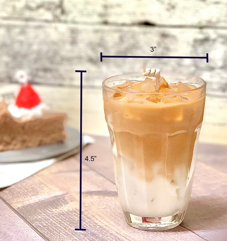 May include: A clear glass with a 3 inch diameter and 4.5 inch height filled with iced coffee. The coffee is layered with a light brown layer on top of a white layer.