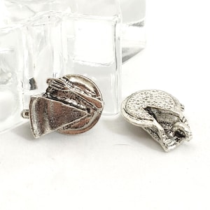 May include: Two silver-toned cufflinks with a detailed design. One cufflink features a circular shape with a triangular element, while the other has a rounded, textured surface. The cufflinks are set against a white background.