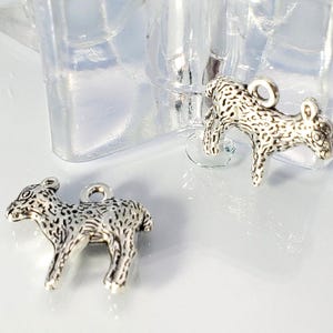May include: Two small, silver-colored deer charms. Each charm is detailed with a spotted pattern and a loop for attaching to jewelry. The charms are set against a bright, neutral background.
