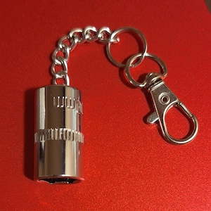 May include: A silver keychain with a small socket wrench attached to a silver chain and a silver clasp.
