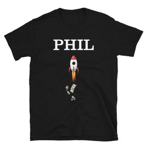 Puede incluir: Camiseta negra con texto blanco que dice "PHIL" y un cohete de dibujos animados lanzando dinero.