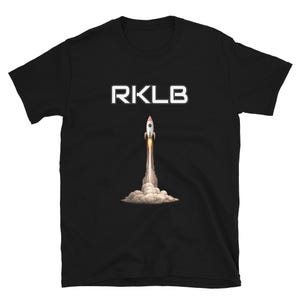 May include: Black t-shirt featuring the white text "RKLB" above a graphic of a rocket launching into space. The rocket is white and orange with a trail of smoke and fire.