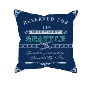 Könnte beinhalten: Ein marineblaues Zierkissen mit weißem Text, der "RESERVED FOR JUDY THE WORLD'S GREATEST SEATTLE FAN" lautet. Auf dem Kissen steht auch "The world's greatest sports fan. The world's No. 1 Mom."