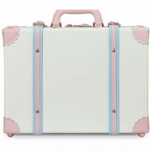 May include: A pink and white vintage-style suitcase handbag with a white shoulder strap and a short, brown strap. The handbag has a printed design of women and a dog. The text "on you and me of the world Beautiful" is printed on the front of the bag.