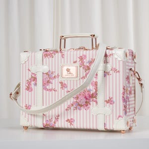 May include: A white vintage-style train case with brown leather accents and a metal latch. The case is shown in three different positions: closed, open, and with a short strap attached to a handle. The text 'Multifunctional Train Case' is above the case. The text 'Long Strap(used as shoulder bag)' is below the case with the long strap. The text 'Short Strap(fastened to suitcase)' is below the case with the short strap.