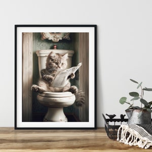 Könnte beinhalten: Eine getigerte Katze sitzt auf einer weißen Toilette und liest eine Zeitung. Die Katze trägt ein weißes Halsband und hat einen ernsten Gesichtsausdruck. Die Toilette befindet sich in einem Badezimmer mit grüner Tapete und einem dekorativen Spiegel.