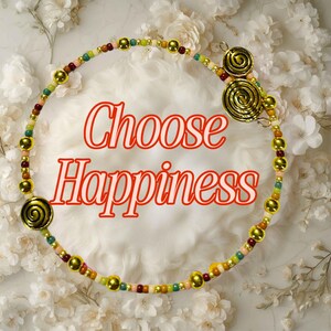 May include: A beaded necklace with gold-colored spiral accents and gold beads. The necklace is multi-colored with red, green, yellow, and pink beads. The words "Choose Happiness" are written in red script.