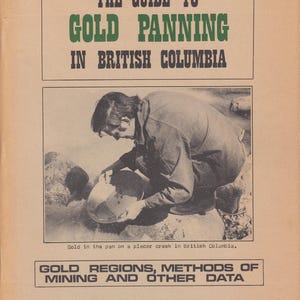 May include: A vintage book cover with the title "The Guide to Gold Panning in British Columbia." The image depicts a person panning for gold. The text below reads "Gold Regions, Methods of Mining and Other Data" by N. L. Barlee.