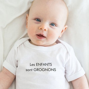 May include: A white baby onesie with the text "Les ENFANTS sont GROGNONS" in black.