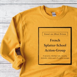 May include: Mustard yellow sweatshirt with the text "Ennui-sur-Blasé Prison" and "French Splatter-School Action-Group" in a black box. The text below reads "A dynamic, talented, lusty, slovenly, alcoholic, violent pack of creative savages."