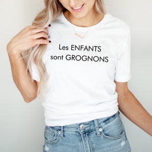 May include: White t-shirt with black text that reads "Les ENFANTS sont GROGNONS".