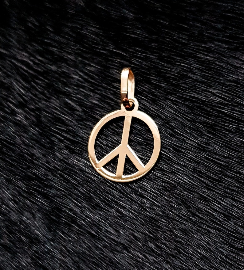 May include: A gold peace sign pendant charm. The charm is a simple, circular design with a peace symbol inside.