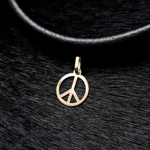 May include: A gold peace sign pendant necklace on a black leather cord.