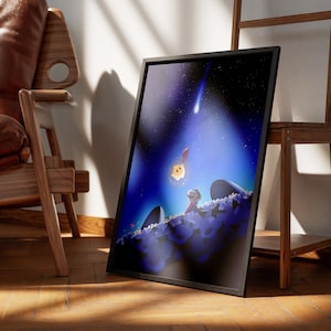 Puede incluir: Impresi&oacute;n art&iacute;stica enmarcada que presenta una ilustraci&oacute;n caprichosa de una escena nocturna estrellada. Una estrella fugaz cruza un cielo azul profundo, iluminando a un ni&ntilde;o y una criatura brillante. La obra de arte se exhibe en un suelo de madera.