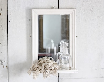Stare, małe szwedzkie lustro z półką, w kolorze złamanej bieli, do wystroju domu w stylu rustykalnym.