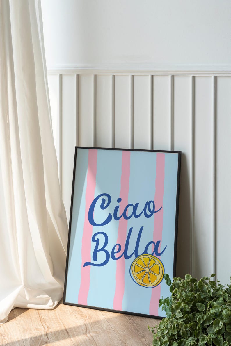 May include: A black framed print with a blue and pink striped background. The print says "Ciao Bella" in blue cursive lettering with a yellow lemon slice graphic.