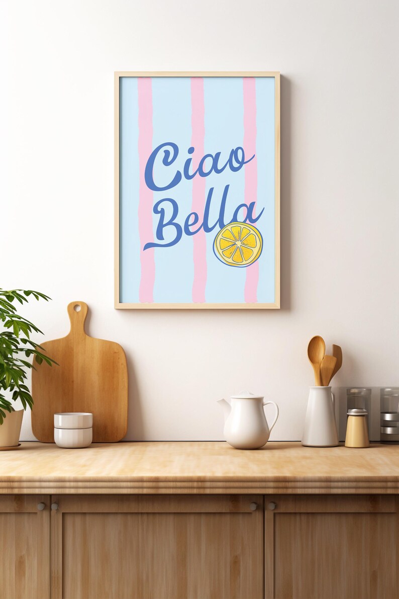 May include: A framed print with a blue and white striped background and the text "Ciao Bella" in blue cursive lettering. A yellow lemon slice is centered below the text.