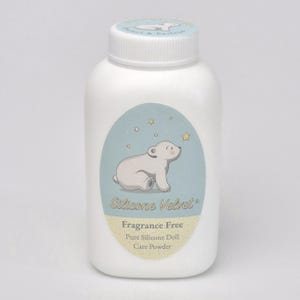 Puede incluir: Una botella de plástico blanco de Silicone Velvet Pure Silicone Doll Care Powder. La botella tiene una tapa de rosca blanca y una etiqueta azul claro con un oso polar de dibujos animados y estrellas. La etiqueta también incluye el texto "Sin fragancia".