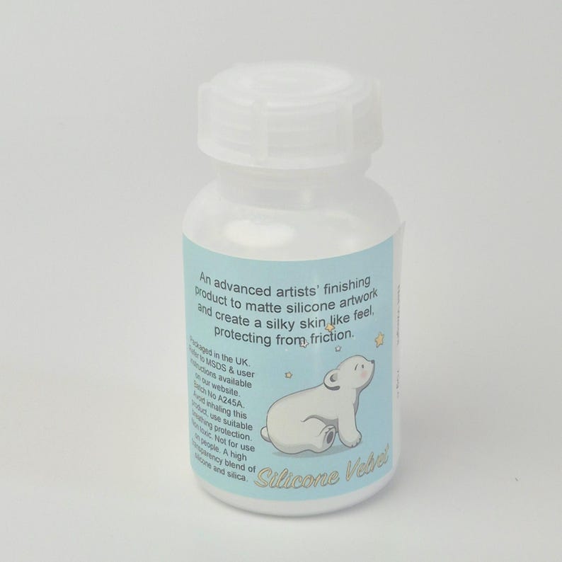 May include: A white plastic bottle with a white cap. The label is light blue with text and a cartoon polar bear illustration. The text reads "Silicone Velvet".