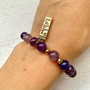 May include: Purple and gold beaded bracelet with a gold charm that says "ones you love are warm in my heart".