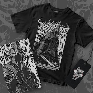 May include: Black t-shirt with a white graphic of a knight holding a sword, with text. A matching print and a tag with a skeleton design are also visible. The shirt has short sleeves.