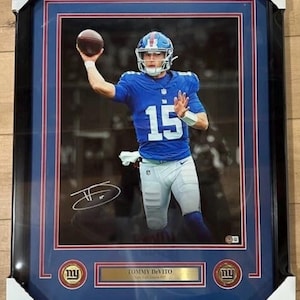 Puede incluir: Foto enmarcada de un jugador de fútbol americano con uniforme azul, número 15, lanzando un balón. El marco negro tiene un borde azul y rojo, e incluye una placa con el nombre "Tommy DeVito".