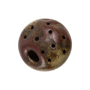 May include: A ceramic ocarina in a spherical shape, featuring a mottled finish in shades of brown, red, and olive green. The instrument has multiple circular holes and a larger opening, suggesting it's a wind instrument.