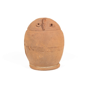 以下が含まれることがあります： シンプルな顔のデザインが施された茶色の粘土製の壺。壺には目となる小さな穴が2つと鼻となる線が1本あります。壺は底に紐で結ばれています。