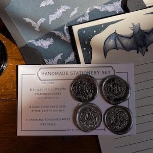 May include: Handmade stationery set featuring illustrated paper and envelopes with bat designs. Includes four adhesive-backed wax seals. The set includes 8 sheets of half-letter sized paper and 4 envelopes, each approximately 4.5 x 5.75 inches. The text on the card reads "HANDMADE STATIONERY SET".