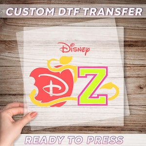 Peut inclure: Un transfert DTF avec le logo Disney, une pomme rouge avec une bouchée, et la lettre "Z" en vert néon avec un contour rose. Les mots "CUSTOM DTF TRANSFER" et "READY TO PRESS" sont imprimés sur le transfert.