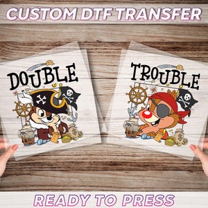May include: Two DTF transfer sheets with pirate-themed cartoon characters. One features a chipmunk in a pirate hat, the word "DOUBLE", and a pirate flag. The other shows a chipmunk with an eye patch, the word "TROUBLE", and a pirate flag. Text at the top reads "CUSTOM DTF TRANSFER".