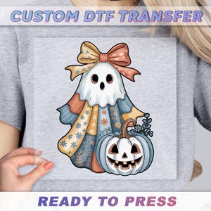 a person wearing a gray t-shirt with a custom DTF transfer of a Halloween-themed ghost and pumpkin.