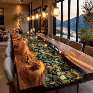 May include: A long rectangular dining table featuring two natural live-edge wood slabs on the sides with a central river section filled with smooth, multi-colored river stones encased in clear resin, accompanied by several upholstered chairs.