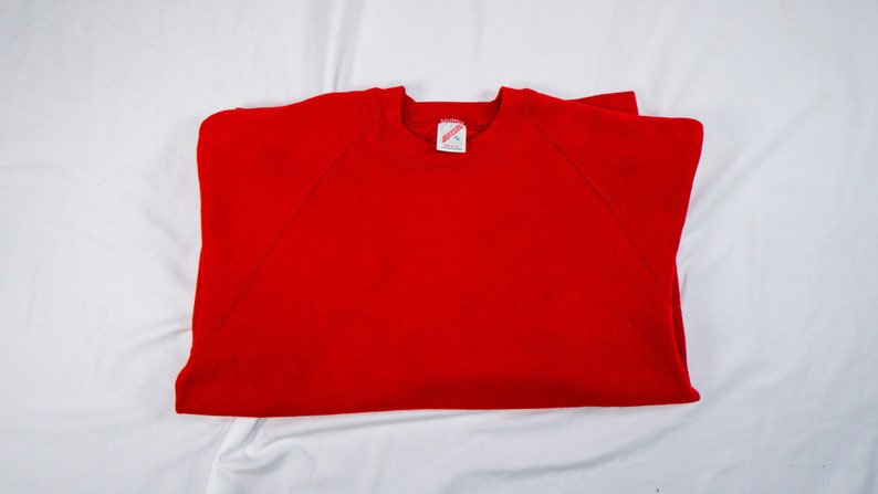 May include: A red sweatshirt with a white tag that says "Hanes" on it.