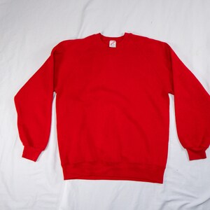 May include: A solid red sweatshirt with a crew neck.