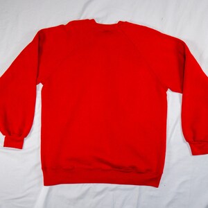 May include: A solid red sweatshirt with long sleeves and a crew neck.
