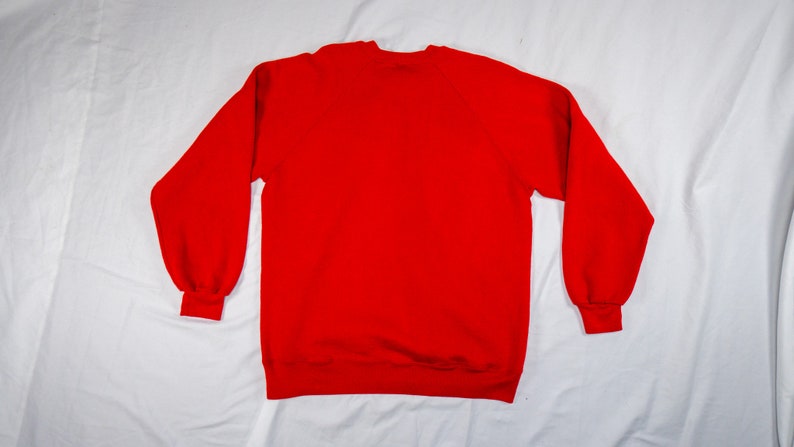 May include: A solid red sweatshirt with long sleeves and a crew neck.