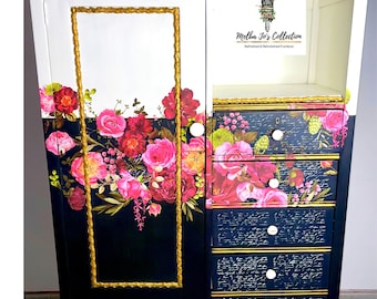Könnte beinhalten: Ein weißer Schrank mit goldenen Akzenten und floralen Mustern auf den Türen. Der Schrank hat vier Schubladen mit schwarz-weißen Mustern auf den Fronten. Der Schrank ist mit einem goldenen Pinsel und dem Text "Melba Jo's Collection" in Schwarz verziert.