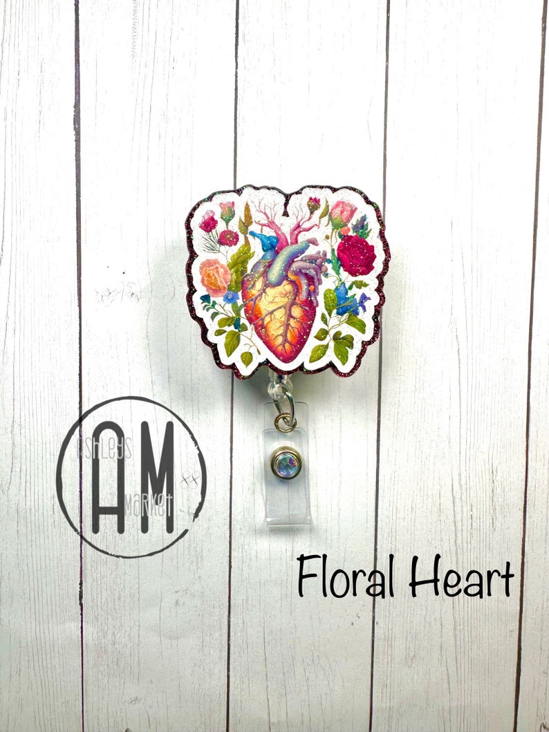 May include: A floral heart-shaped badge reel with a sparkly rhinestone charm. The heart is surrounded by flowers and leaves in shades of pink, red, and green. The text "Floral Heart" is printed below the badge reel.