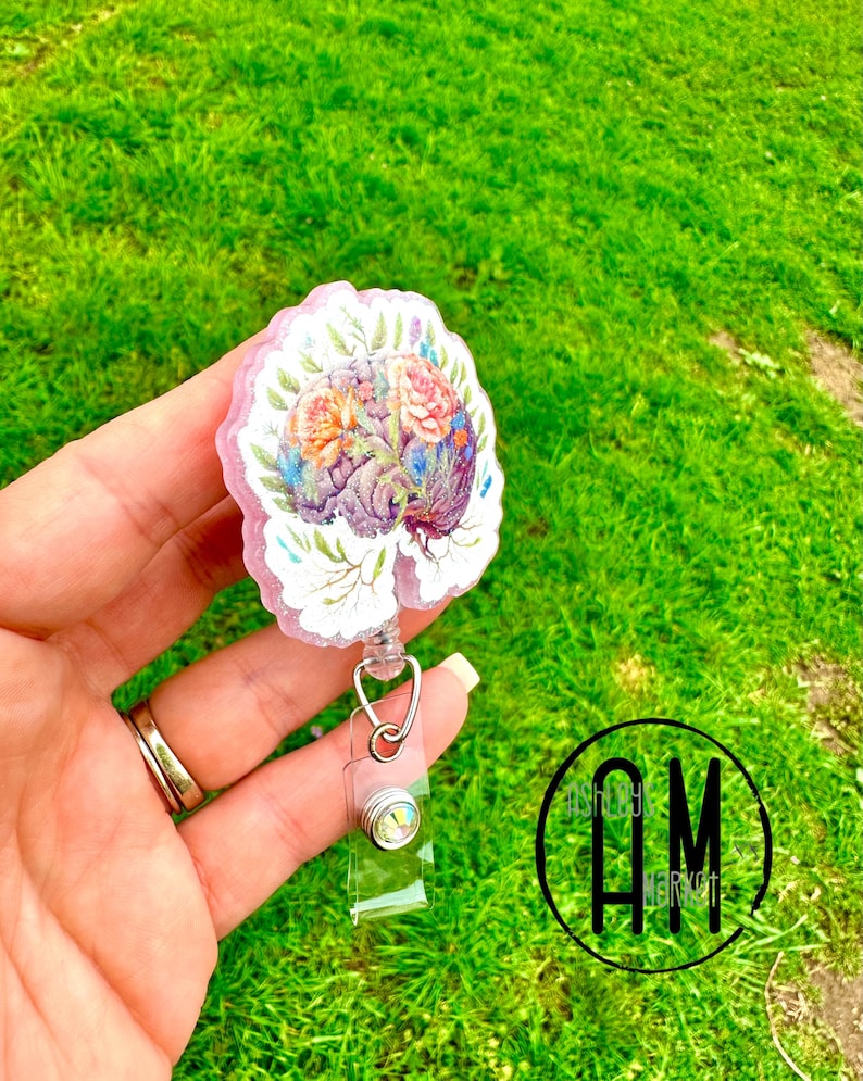 May include: A pink floral brain-shaped badge reel with a clear retractable badge holder and a sparkly rhinestone.