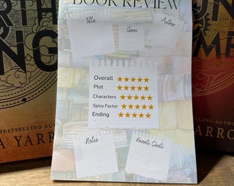 Könnte beinhalten: Eine Buchrezensionskarte mit weißem Hintergrund und einem goldenen Sterne-Bewertungssystem. Die Karte hat Abschnitte für Titel, Genre, Autor, Gesamtbewertung, Handlung, Charaktere, Würzefaktor, Ende, Notizen und Lieblingszitat. Die Karte liegt auf einer Holzoberfläche.