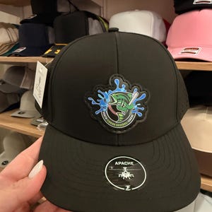 May include: Black baseball cap with a curved brim. The cap features a patch with a baseball bat, a fish, and the text "South Florida Baseball League." The word "Apache" is printed on the front.
